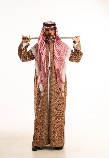 حمل السيف بتباهي وفخر احتفالا بيوم بدينا ١٧٢٧م، النظر إلى الكاميرا بإيماءات الاعتزاز، ارتداء الأزياء الشعبية في المناسبات الوطنية, بورتريه لرجل عربي خليجي سعودي يرتدي الشماغ والدقلة ، ذكرى تأسيس الدولة السعودية الأولى في 22 فبراير، صورة لكامل الجسم، خلفية بيضاء