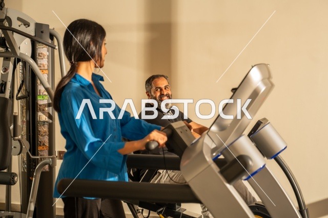 Exchanging entertaining conversations while exercising, maintaining fitness and physical agility, a Saudi Arabian man and woman wearing sports attire and engaging in morning exercise, a healthy lifestyle, spending enjoyable times with family outdoors.
