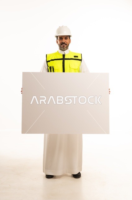 عرض موك اب أبيض فارغ كبير، بورتريه لمهندس عربي خليجي سعودي يرتدي الثوب التقليدي والسترة وخوذة الحماية يعمل في القطاع الهندسي في المملكة العربية السعودية، ادارة المشاريع الهندسية والانشاءات، مفهوم دراسة المخطط ومشروع البناء، الجسم بالطول الكامل، خلفية بيضاء