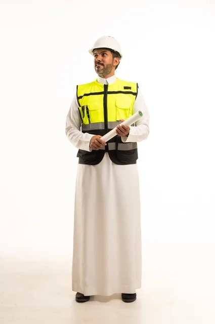 وظيفة ومهنة هندسية شبابية، بورتريه لمهندس عربي خليجي سعودي يرتدي الثوب التقليدي والسترة وخوذة الحماية يعمل في القطاع الهندسي في المملكة العربية السعودية، ادارة المشاريع الهندسية والانشاءات، مفهوم دراسة المخطط ومشروع البناء، الجسم بالطول الكامل، خلفية بيضاء