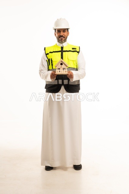 إنشاء واعمار العقارات، وظيفة ومهنة هندسية شبابية، بورتريه لمهندس عربي خليجي سعودي يرتدي الثوب التقليدي والسترة وخوذة الحماية يمسك بيده مجسم بيت خشبي صغير، العمل في القطاع الهندسي، ادارة المشاريع الهندسية والانشاءات، خلفية بيضاء