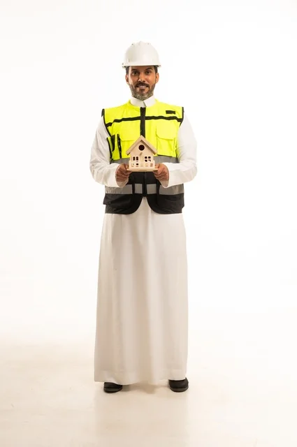 Construction and development of real estate, a job and engineering profession for youth, a portrait of a Saudi Arabian Gulf engineer wearing traditional attire and a safety helmet holding a small wooden house model in his hand, working in the engineering sector, managing engineering projects and constructions, white background.