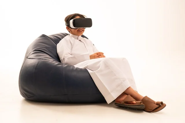 قضاء أوقات ممتعة ودمج التكنولوجيا في الحياة اليومية، التفاعل و المتعة و التسلية بمشاهدة الأفلام و ألعاب العالم الافتراضي ، بورتريه لطفل عربي خليجي سعودي سعيد يرتدي نظارة الواقع الإفتراضي ثلاثية الأبعاد الفريدة و العجيبة، تقنيات و ألعاب ، خلفية بيضاء