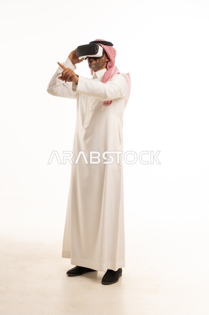 The integration and interaction with the imaginary world, a portrait of a Saudi Arabian Gulf man wearing traditional thobe and ghutrah, with 3D virtual reality glasses trying to embody something, merging modern technologies and technology with fun and entertainment, full-body, white background.