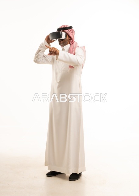 The integration and interaction with the imaginary world, a portrait of a Saudi Arabian Gulf man wearing traditional thobe and ghutrah, with 3D virtual reality glasses trying to embody something, merging modern technologies and technology with fun and entertainment, full-body, white background.