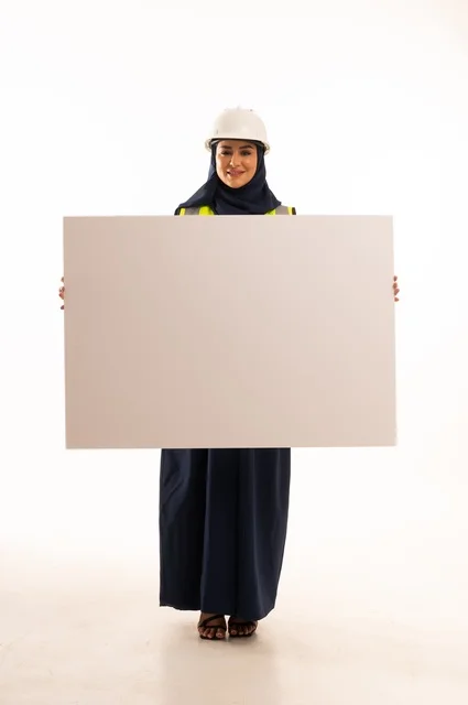 Marketing offers and advertisements, women's professions and jobs in the engineering sector, the role of structural engineering in the development of Saudi society, a portrait of a Muslim Arab Gulf engineer wearing a white helmet and safety vest holding a white board, full-body, white background.