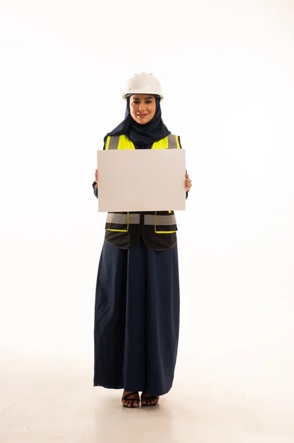 موك أب مستطيل أبيض، العروض والأعلانات التسويقية، دور الهندسة الإنشائية في تطور المجتمع السعودي, بورتريه لمهندسة عربية خليجية سعودية مسلمة محجبة ترتدي الخوذة البيضاء وسترة الحماية تحمل لوحة بيضاء، الجسم بالطول الكامل، خلفية بيضاء