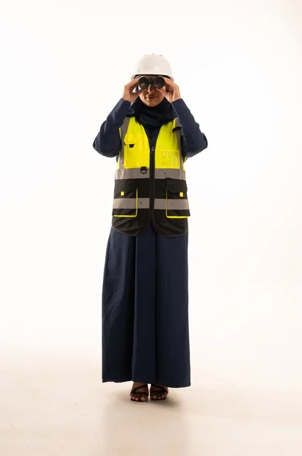 The role of structural engineering in the development of Saudi society, looking through a lens at something and standing with a straight back, professions and jobs for women in the engineering sector, a portrait of an Arab Gulf Saudi Muslim woman wearing a hijab, wearing a white helmet and safety vest, full-body, white background.