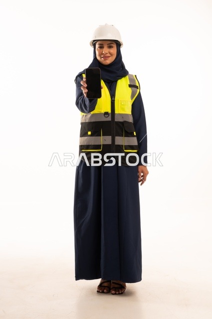 A black background displayed on a mobile phone and standing with a straight back, women's professions and jobs in the engineering sector, the role of structural engineering in the development of Saudi society, a portrait of an Arab Gulf Saudi Muslim engineer wearing a white helmet and safety vest, full-body, white background.