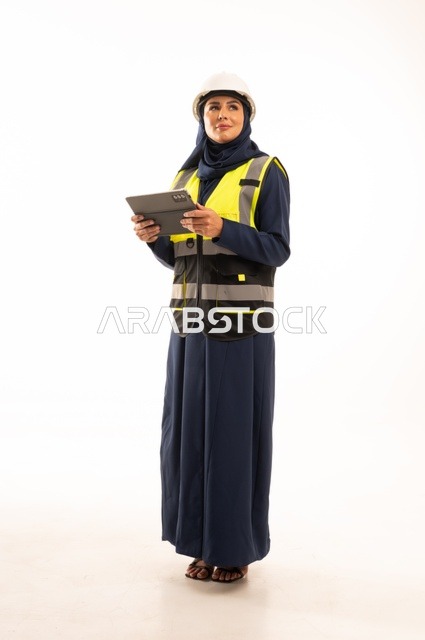 مهن ووظائف نسائية في القطاع الهندسي, دور الهندسة الإنشائية في تطور المجتمع السعودي,  بورتريه لمهندسة عربية خليجية سعودية مسلمة محجبة ترتدي الخوذة البيضاء وسترة الحماية تعمل على الجهاز اللوحي، الوقوف بظهر مشدود، الجسم بالطول الكامل، خلفية بيضاء