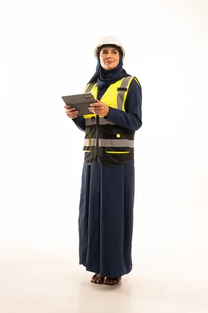 مهن ووظائف نسائية في القطاع الهندسي, دور الهندسة الإنشائية في تطور المجتمع السعودي,  بورتريه لمهندسة عربية خليجية سعودية مسلمة محجبة ترتدي الخوذة البيضاء وسترة الحماية تعمل على الجهاز اللوحي، الوقوف بظهر مشدود، الجسم بالطول الكامل، خلفية بيضاء