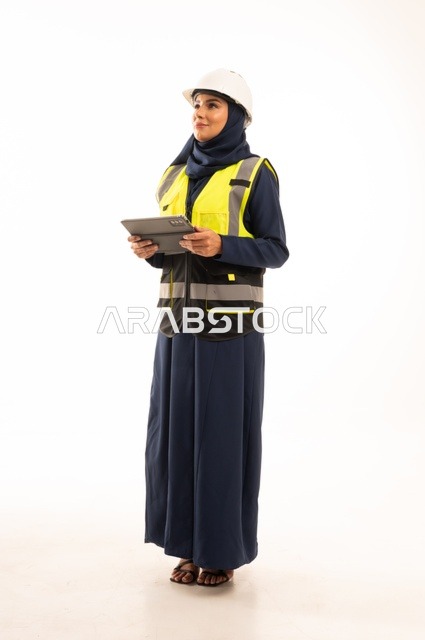 Standing with a straight back, women's professions and jobs in the engineering sector, the role of structural engineering in the development of Saudi society, a portrait of a Muslim Arab Gulf Saudi female engineer wearing a white helmet and safety vest working on a tablet, full-body, white background.