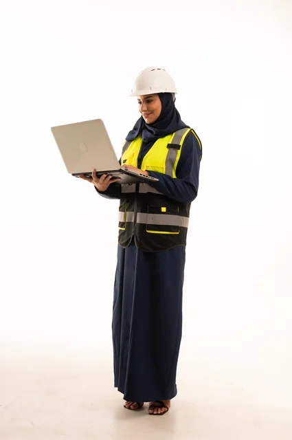 Integrating technology into work, the role of structural engineering in the development of Saudi society, the role of structural engineering in the development of Saudi society, a portrait of a Gulf Arab Saudi Muslim female engineer wearing a white helmet and safety vest working on a mobile device, full-body, white background.