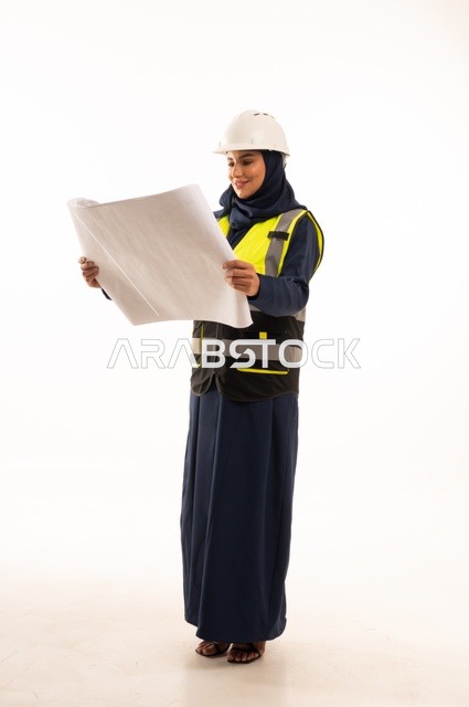 متابعة وقراءة المخططات الهندسية، دور الهندسة الإنشائية في تطور المجتمع السعودي، دور الهندسة الإنشائية في تطور المجتمع السعودي, بورتريه لمهندسة عربية خليجية سعودية مسلمة محجبة ترتدي الخوذة البيضاء وسترة الحماية، الجسم بالطول الكامل، خلفية بيضاء