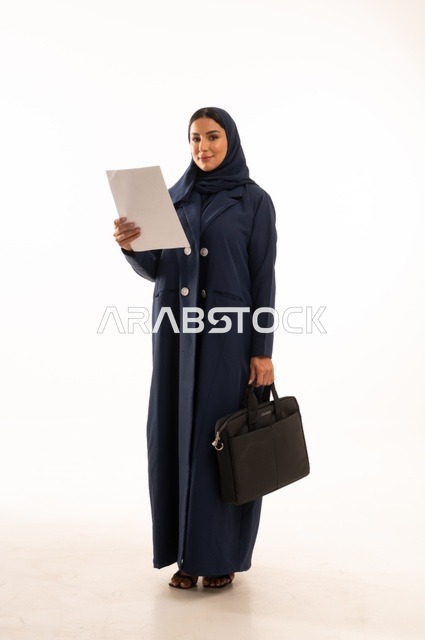 متابعة المهام اليومية المكتبية وقراءة الملاحظات, بورتريه لإمرأة عربية خليجية سعودية مبتسمه ترتدي العباءة تحمل حقيبة الأعمال وورقة بيضاء, أناقة النساء الخليجيات, الاهتمام بالمظهر الخارجي, الجسم بالطول الكامل، خلفية بيضاء