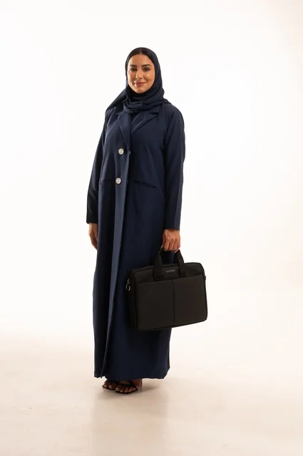 الوقوف باستقامة بإيماءات الجدية والثقة بالنفس, بورتريه لإمرأة عربية خليجية سعودية مبتسمه ترتدي العباءة تحمل حقيبة الأعمال, سيدة سعودية تنظر بايماءت السعاده و السرور, أناقة النساء الخليجيات, الاهتمام بالمظهر الخارجي, الجسم بالطول الكامل، خلفية بيضاء