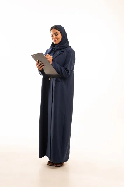 كتابة وتدوبن الملاحظات على لوح كليب بورد, بورتريه لإمرأة عربية خليجية سعودية مبتسمه ترتدي العباءة, سيدة سعودية تنظر بايماءت السعاده و السرور, أناقة النساء الخليجيات, الاهتمام بالمظهر الخارجي, الجسم بالطول الكامل، خلفية بيضاء