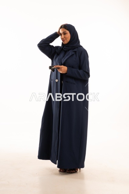 تعابير وجه ويد تدل على الخسارة والحزن، مفهوم الاندماج والتفاعل باللعب ألعاب البلايستيشن، قضاء أوقات ممتعة, بورتريه لشابة عربية خليجية سعودية ترتدي العباءة، سيده سعوديه تمسك بيدها عصا التحكم عن بعد تلعب بألعاب الفيديو، الجسم بالطول الكامل، خلفية بيضاء