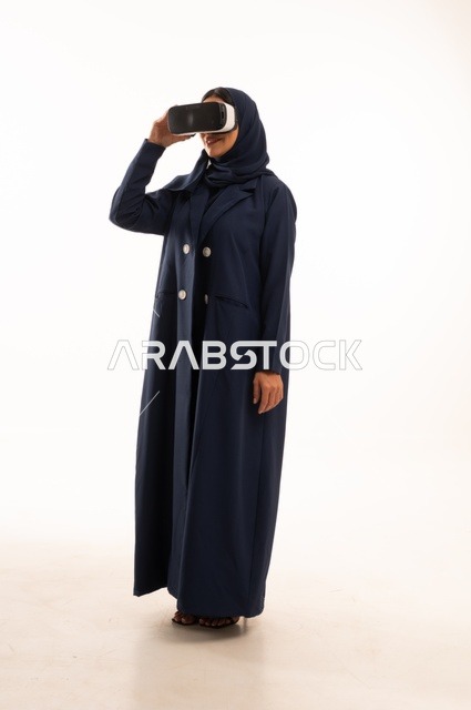 قضاء أوقات ممتعة ودمج التكنولوجيا في الحياة اليومية، بورتريه لإإمرأة عربية خليجية سعودية سعيدة ترتدي نظارة الواقع الإفتراضي ثلاثية الأبعاد الفريدة و العجيبة، التفاعل و المتعة و التسلية بمشاهدة الأفلام و ألعاب العالم الافتراضي ، تقنيات و ألعاب ، خلفية بيضاء