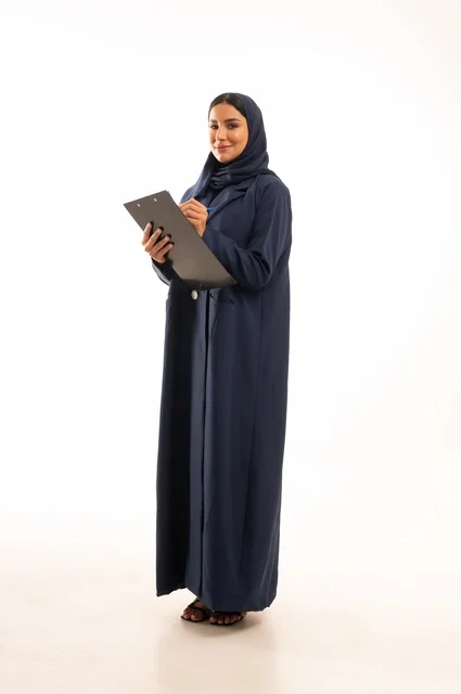 كتابة وتدوبن الملاحظات على لوح كليب بورد, بورتريه لإمرأة عربية خليجية سعودية مبتسمه ترتدي العباءة, سيدة سعودية تنظر بايماءت السعاده و السرور, أناقة النساء الخليجيات, الاهتمام بالمظهر الخارجي, الجسم بالطول الكامل، خلفية بيضاء
