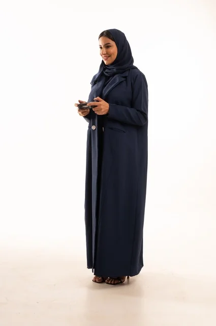 Electronic games and modern devices, the concept of integration and interaction in playing PlayStation games, spending enjoyable times, a portrait of a young Arab Gulf Saudi woman wearing an abaya, a Saudi woman holding a remote control playing video games, full-body, white background.