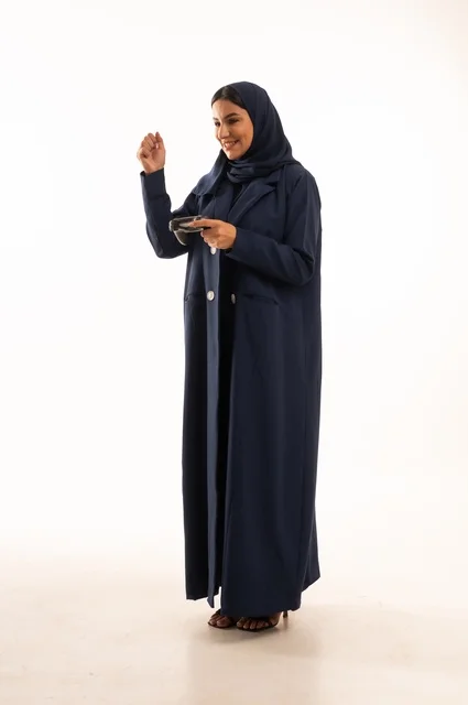 قضاء أوقات ممتعة, بورتريه لشابة عربية خليجية سعودية ترتدي العباءة، سيده سعوديه تمسك بيدها عصا التحكم عن بعد تلعب بألعاب الفيديو بإيماءات وجه ويدين مختلفة تدل على الفوز والإنتصار، الجسم بالطول الكامل، خلفية بيضاء