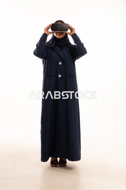 قضاء أوقات ممتعة ودمج التكنولوجيا في الحياة اليومية، بورتريه لإإمرأة عربية خليجية سعودية سعيدة ترتدي نظارة الواقع الإفتراضي ثلاثية الأبعاد الفريدة و العجيبة، التفاعل و المتعة و التسلية بمشاهدة الأفلام و ألعاب العالم الافتراضي ، تقنيات و ألعاب ، خلفية بيضاء