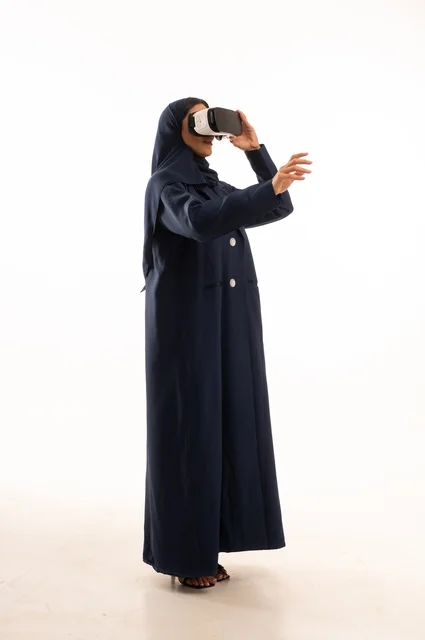 Pointing with the hand at something being watched, a portrait of a happy Saudi Gulf Arab woman wearing unique and amazing 3D virtual reality glasses, interacting and enjoying watching movies and playing virtual world games, technologies and games, white background.