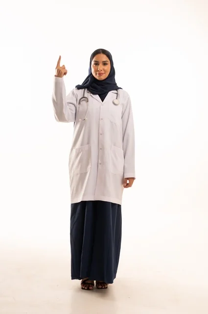 تعابير يد اذهب إلى الأعلى النظر إلى الكاميرا بايماءات الثقة بالنفس، الاهتمام بالمظهر الخارجي، تقديم الفحص الطبي والخدمات العلاجية، بورتريه مقرب لطبيبة عربية خليجية سعودية محجبة مبتسمة ترتدي معطف الطبيب وتضع السماعات الطبية، مفهوم الأنوثة والنعومة، خلفية بيضاء