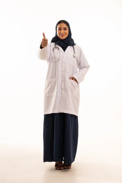 Thumbs up gesture, looking at the camera with self-confidence gestures, attention to appearance, providing medical examinations and treatment services, a close-up portrait of a smiling Saudi Gulf Arab female doctor wearing a doctor's coat and stethoscope, the concept of femininity and softness, white background.