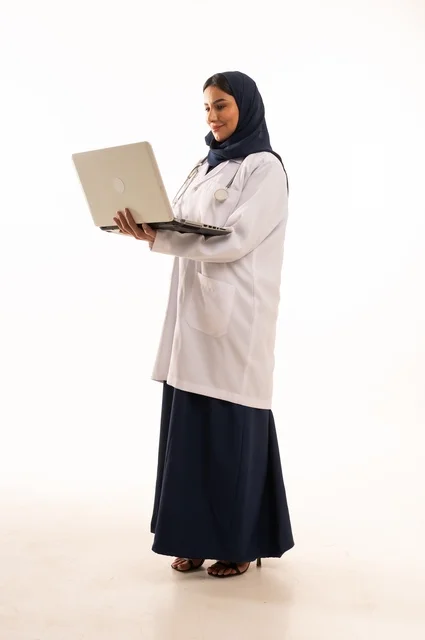 متابعة المهام اليومية باستخدام التكنولوجيا، استخدام التقنية الحديثه المتطورة في الحياة العملية، بورتريه لإمرأة عربية خليجية سعودية ترتدي الحجاب والعباءة تقوم بالعمل على الحاسب المحمول، متابعة وتصفح مواقع التواصل، صورة الجسم بالطول الكامل، خلفية بيضاء