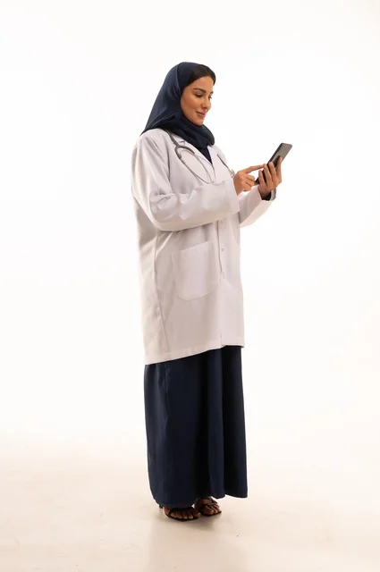 تعابير وايماءات الاندماج والسرور، استخدام التقنية الحديثه المتطورة في الحياة العملية، بورتريه لإمرأة عربية خليجية سعودية ترتدي الحجاب والعباءة تقوم بالعمل على الهاتف المحمول، متابعة وتصفح مواقع التواصل الاجتماعي، صورة الجسم بالطول الكامل، خلفية بيضاء