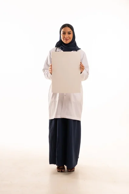 العروض والإعلانات التسويقية, لوحات توضيحية ووسائل تعليمية, بورتريه لطبيبة عربية خليجية سعودية ترتدي العباءة والمئزر الأبيض تمسك بيديها لوحة بيضاء مستطيلة فارغة، شابة سعودية تنظر إلى الكاميرا بتعابير الحزم والجدية، موك اب مستطيل أبيض, خلفية بيضاء
