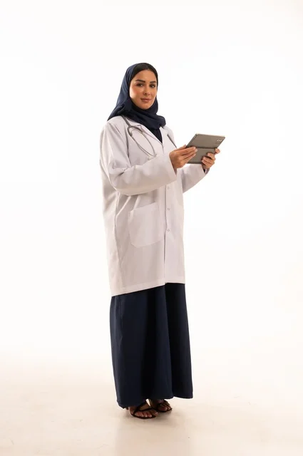 متابعة العمل باستخدام جهاز لوحي، استخدام التقنية الحديثه المتطورة في الحياة العملية، بورتريه لإمرأة عربية خليجية سعودية ترتدي الحجاب والعباءة تقوم بالعمل على التابلت، تصفح مواقع التواصل، صورة الجسم بالطول الكامل، خلفية بيضاء