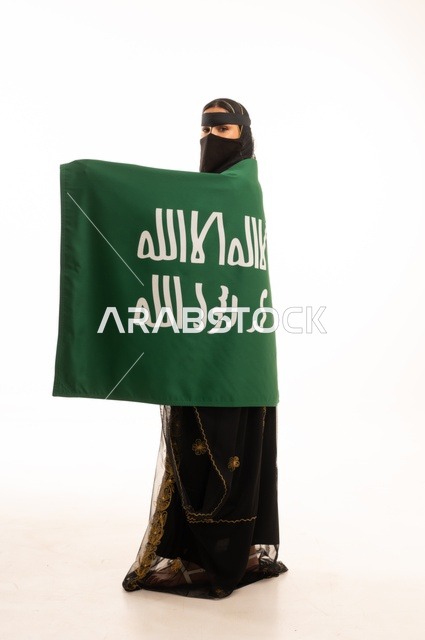 The establishment of the first Saudi state on February 22, the anniversary of our beginning in 1727 AD, wearing the traditional attire of the central region during popular and national occasions, a portrait of an Arab Gulf Saudi woman wearing the burqa and shayla holding the flag and emblem of the Foundation Day with expressions of pride and honor, full-body, white background.