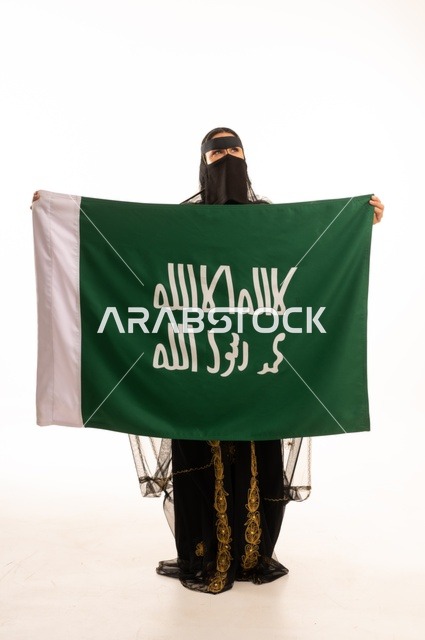 تأسيس الدولة السعودية الأولى 22 فبراير، ذكرى يوم بدينا 1727 م، ارتداء زي المنطقة الوسطى في المناسبات الشعبية والوطنية, بورتريه لإمرأة عربية خليجية سعودية ترتدي البرقع والشيلة تمسك راية وشعار يوم التأسيس بتعابير الفخر والاعتزاز, الجسم بالطول الكامل, خلفية بيضاء