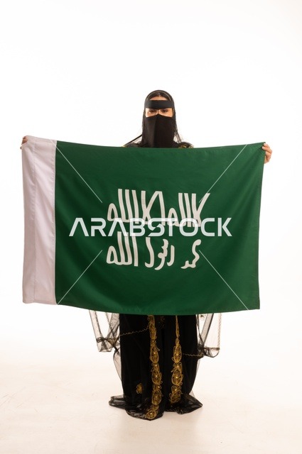 The anniversary of the day we began in 1727 AD, the establishment of the first Saudi state on February 22, wearing the traditional attire of the central region during popular and national occasions, a portrait of a Saudi Gulf Arab woman wearing a burqa and shayla holding the flag and emblem of the Foundation Day with expressions of pride and honor, full-body, white background.