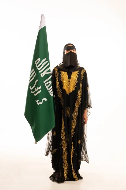 ذكرى يوم بدينا 1727 م، تأسيس الدولة السعودية الأولى 22 فبراير، ارتداء زي المنطقة الوسطى في المناسبات الشعبية والوطنية, بورتريه لإمرأة عربية خليجية سعودية ترتدي البرقع والشيلة تمسك راية وشعار يوم التأسيس بتعابير الفخر والاعتزاز, الجسم بالطول الكامل, خلفية بيضاء