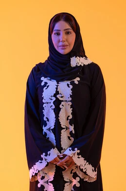 Attention to elegance and concern for external appearance, a Saudi woman looking with expressions of joy and happiness, a portrait of an Arab Gulf Emirati woman wearing an abaya and hijab standing with intertwined hands and gestures of self-confidence.