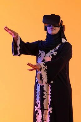 Attempting to grasp something, the concept of fear and terror, using modern electronic technologies, a young Arab Gulf Emirati woman wearing an embroidered abaya and hijab, putting on 3D VR glasses, a Saudi woman standing with gestures of integration and interaction with the virtual world, merging technology with practical life, yellow background.