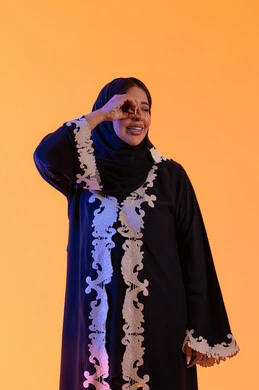 Looking at something, seeing distant things and bringing them closer, a Saudi woman who loves exploration and adventure, a portrait of an Arab Gulf Emirati woman wearing an abaya and hijab, raising her hand with gestures of binoculars and looking with expressions of joy and enjoyment.