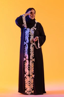 التخطيط المستقبلي للأهداف والطموحات، رؤية الاشياء البعيدة وتقريبها، سيده سعوديه تحب الاستكشاف والمغامرة، بورتريه لامراه عربيه خليجيه اماراتيه ترتدي العباءه والحجاب ترفع  يدها بايماءات منظار وتنظر بتعابير السرور والاستمتاع