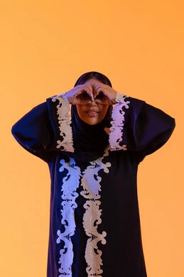 A Saudi woman who loves exploration and adventure, seeing distant things and bringing them closer. A portrait of an Arab Gulf Emirati woman wearing an abaya and hijab, raising her hand with gestures of binoculars and looking with expressions of joy and enjoyment.