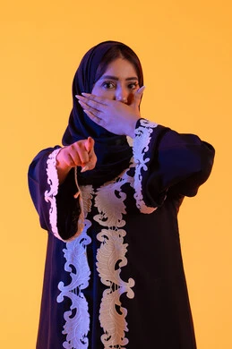 بورتريه لامراه عربيه خليجيه اماراتيه ترتدي العباءه والحجاب تشير بإصبع السبابة لاعلى إلى شيء ، النظر إلى الكاميرا بإيماءات الفرح والسرور، تعابير تشير هذا المكان هنا، تحديد موقع معين ، سيدة سعودية تضع يدها على فمها بتعابير المفاجأه