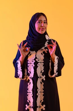 البشاشة والشعور بالسعادة ،سيده سعوديه تشير بتعابير الرضي والموافقة ،  التعبير عن الجودة والاتقان، بورتريه لامراه عربيه خليجيه اماراتيه ترتدي العباءه والحجاب تقوم برفع ايديها بإيماءات الجودة والامتياز والتميز، خلفية صفراء