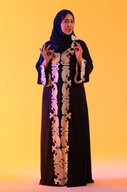 سيده سعوديه تشير بتعابير الرضي والموافقة ، البشاشة والشعور بالسعادة ، التعبير عن الجودة والاتقان، بورتريه لامراه عربيه خليجيه اماراتيه ترتدي العباءه والحجاب تقوم برفع ايديها بإيماءات الجودة والامتياز والتميز، خلفية صفراء