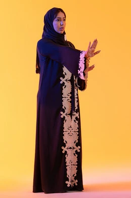 مفهوم الخوف والقلق ، بورتريه مقرب لامراة عربية خليجية إماراتية ترتدي العباءة المطرزة والحجاب تنظر إلى الكاميرا، سيدة سعودية تشير بترك مسافة أمان وطلب التوقف،مد اليدين نحو الأمام في محاولة للدفاع عن النفس،  خلفية صفراء