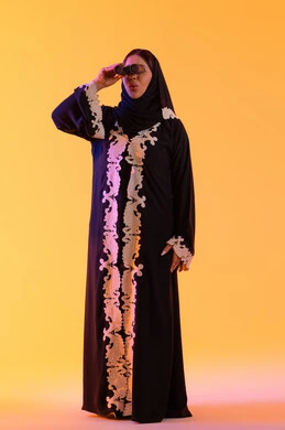 رؤية الاشياء البعيدة وتقريبها، سيده سعوديه تحب الاستكشاف والمغامرة، بورتريه لامراه عربيه خليجيه اماراتيه ترتدي العباءه والحجاب تحمل بيدها منظار ثنائي العينين وتنظر بإيماءات السرور والاستمتاع