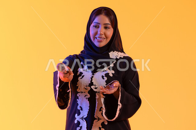 بورتريه لامراه عربيه خليجيه اماراتيه ترتدي العباءه المطرزة والحجاب تمسك بيدها المايكروفون ، سيده سعوديه تغني بإيماءات الحماس والسرور، تعابير الاندماج والتفاعل مع الموسيقي، تقديم العروض الصوتية ، تسجيل مقطع صوتي غنائي، تقديم البرامج الاذاعية، ممارسة موهبة الغناء،خلفية صفراء