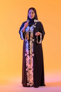 Recording a singing audio clip, presenting radio programs, practicing the talent of singing, a portrait of an Emirati Gulf Arab woman wearing an embroidered abaya and hijab holding a microphone in her hand, a Saudi woman singing with gestures of enthusiasm and joy, expressions of immersion and interaction with the music, presenting audio performances, yellow background.